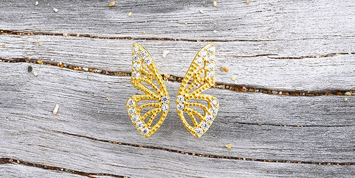 gold butterfly earrings on driftwood