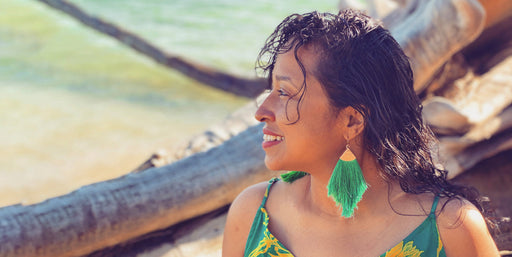 evelyn wearing emerald green long tassel earrings while looking off at the ocean